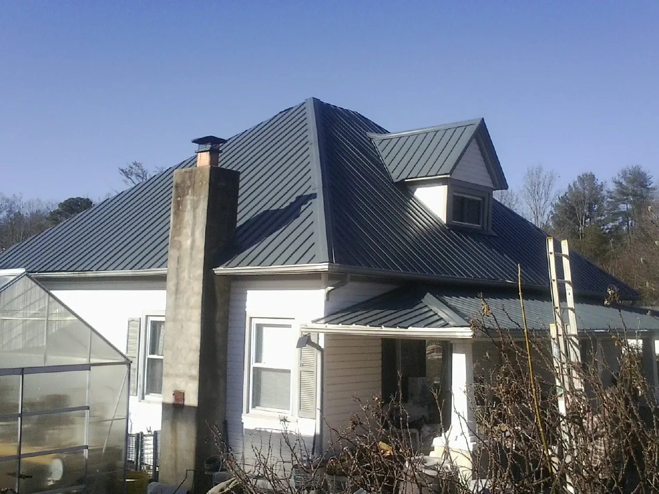 Dark blue standing seam metal roof on a white farmhouse with dormer — Slate & Tile Roof Repair by Roofing Brothers in Clearlake
