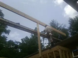 Carpenter setting a ridge beam over a new addition frame — Ice Dam Removal by Roofing Brothers in Clearlake