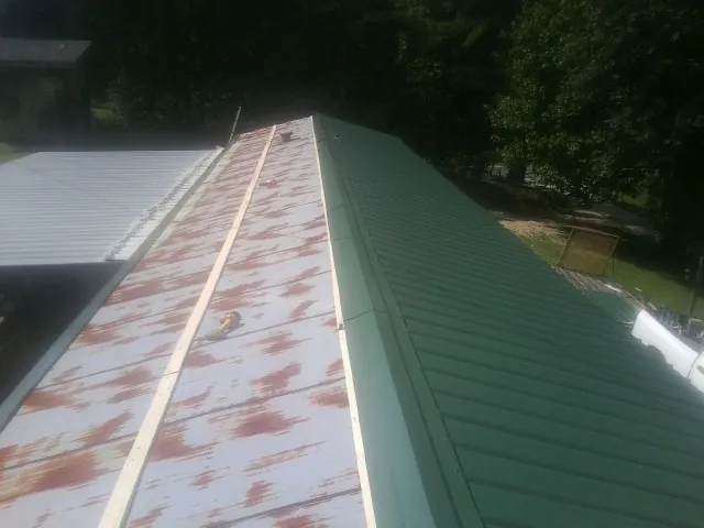 Old rusted panels beside newly installed green metal roofing — Wind Damage Roof Repair by Roofing Brothers in Clearlake