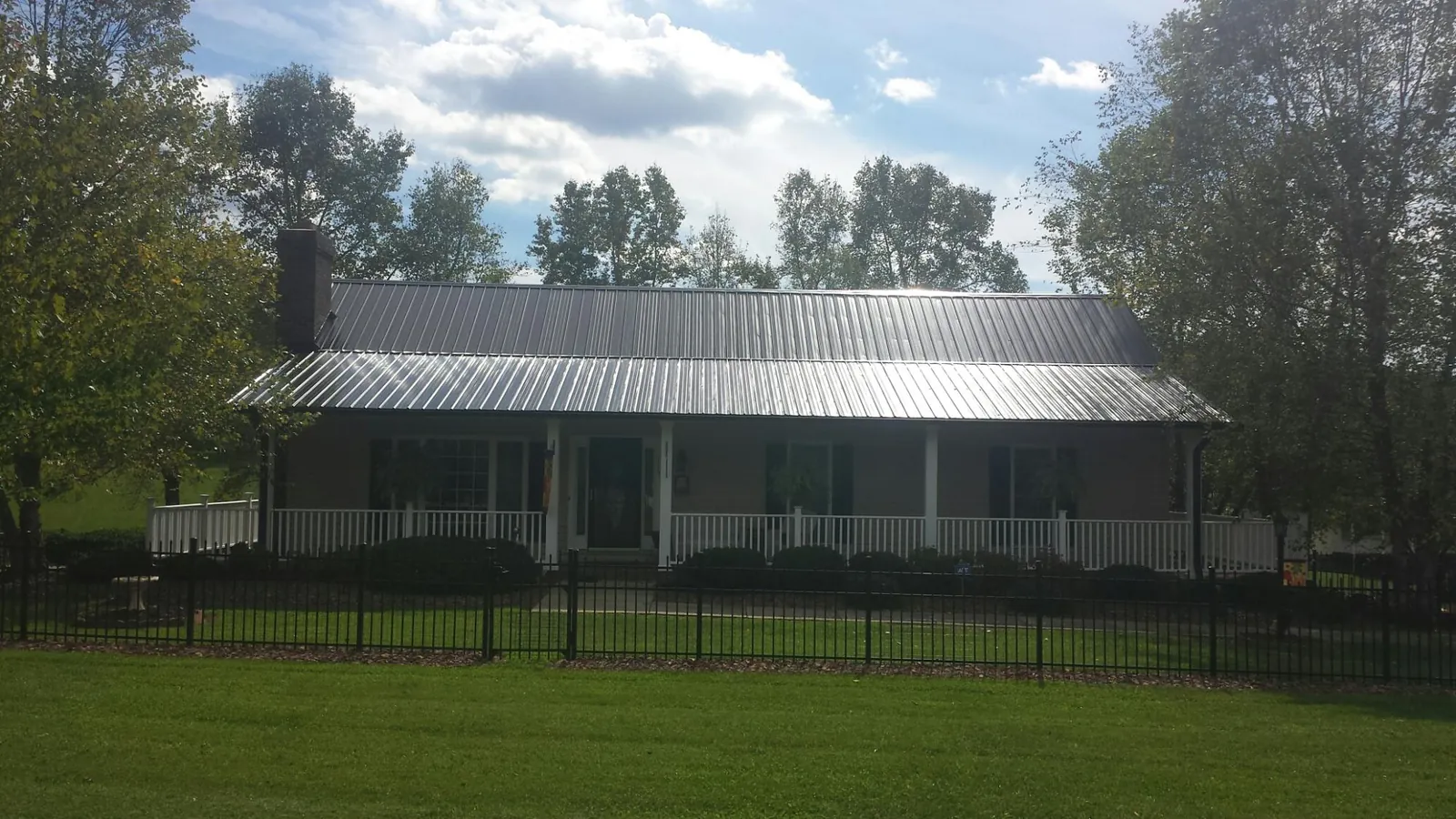 Gray metal roof on a brick ranch with a full width front porch — Gutter Guard Installation work by our crew in Clearlake