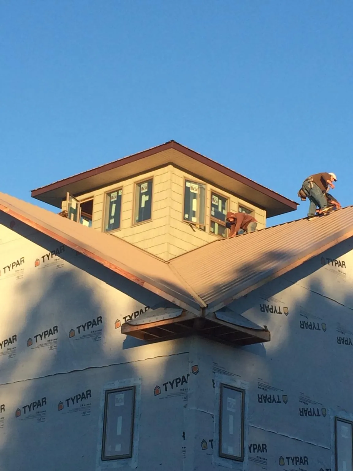 Roofers working around a rooftop cupola on a new metal roof at sunset — Roof Waterproofing in Clearlake by Roofing Brothers